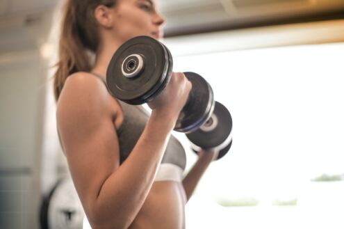Benefits of lifting weights, a woman doing barbell curls