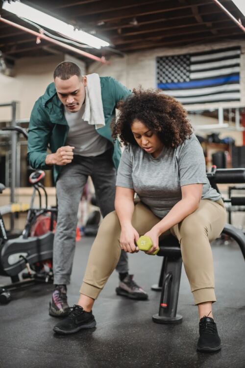 Benefits of regular exercise, a personal trainer encouraging a gym goer